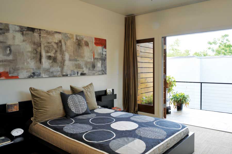 
Wide balcony doors and a floor-to-ceiling curtain allow varying levels of light and breeze into the master bedroom. Local artist Kim Fonder created the painting above the bed.
